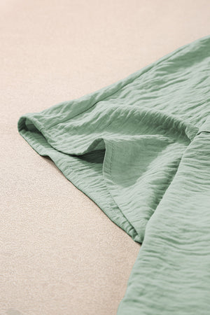 Sage oversized shirt romper with pockets and textured fabric detail.