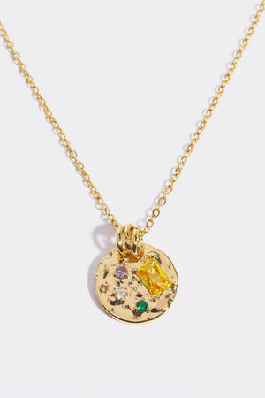 Gold textured disc pendant necklace with colorful gemstone accents