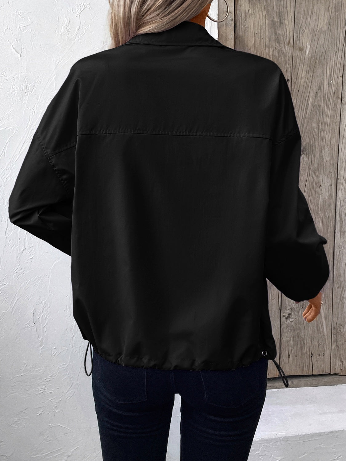 Black nylon bomber jacket with drawstring hem and casual fit.