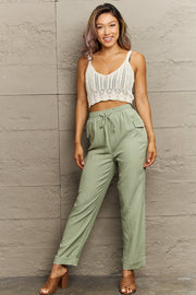 Light green utility drawstring cargo pants with subtle pinstripe texture and flap pockets.