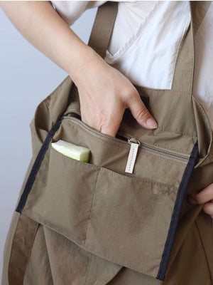 Khaki nylon shoulder bag with exterior slip pockets and zippered compartment.