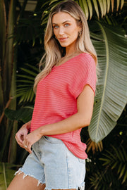 Open-knit dolman sleeve top in watermelon pink acrylic with a boat neckline.