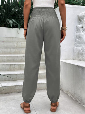 Gray relaxed-fit trousers with smocked waistline and cinched ankles.