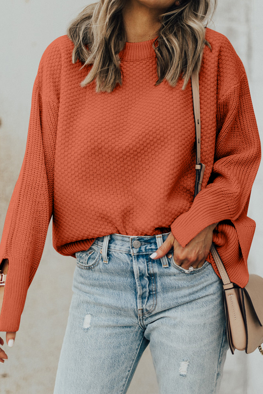 Textured knit sweater in ochre with crew neck and slit sleeves, styled with denim.