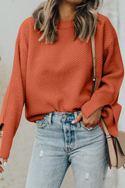 Textured knit sweater in ochre with crew neck and slit sleeves, styled with denim.