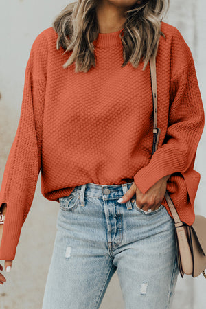 Textured knit sweater in ochre with crew neck and slit sleeves, styled with denim.