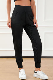 Black joggers with performance fit, elastic waistband, pockets, and cuffed ankles.