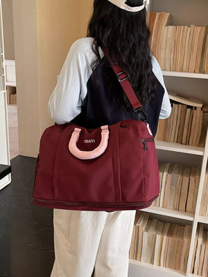 Burgundy nylon travel duffel bag with padded handle and adjustable strap