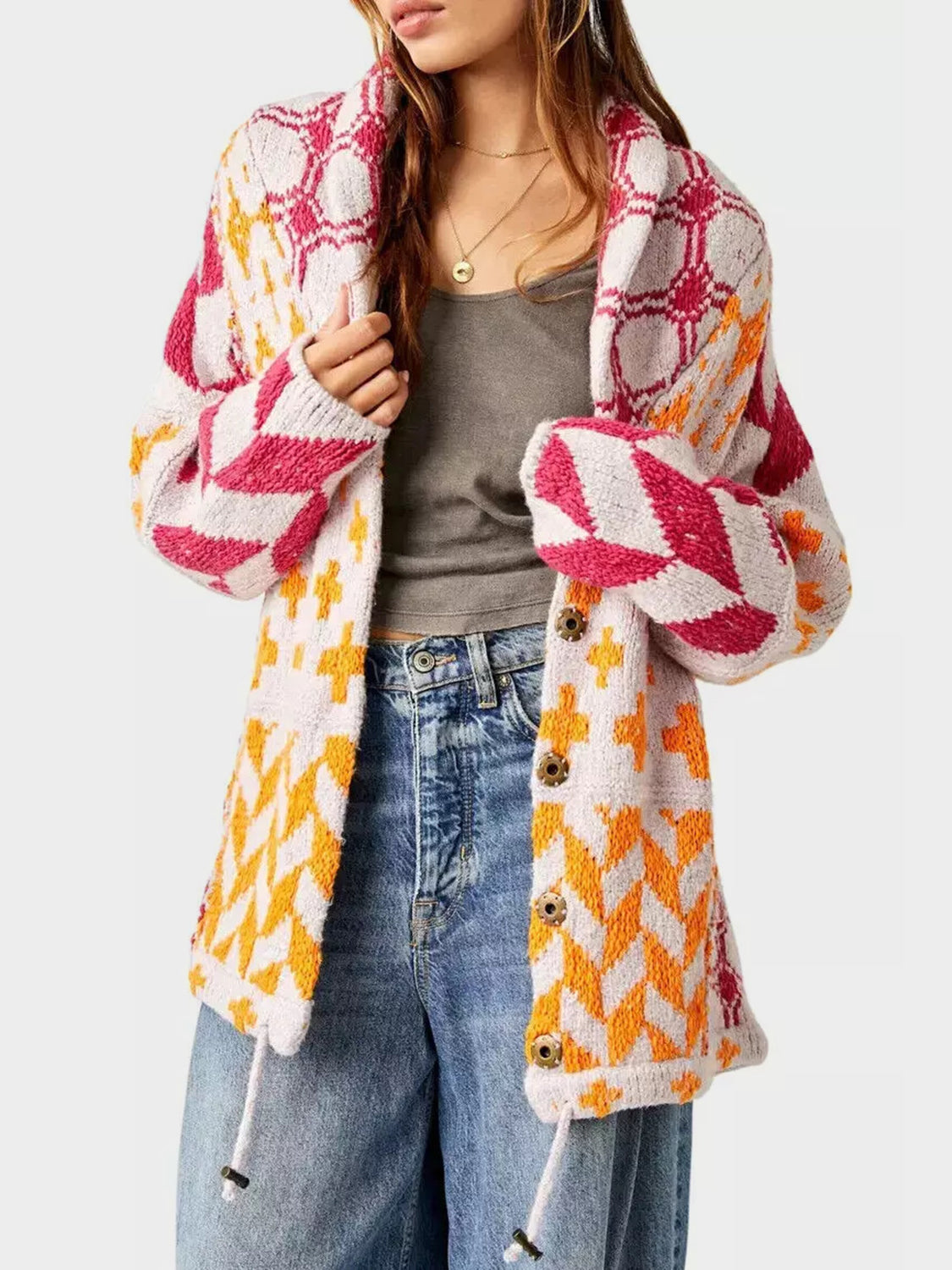 Geometric patchwork knit cardigan with button front and drawstring hem. Features pink, orange, and white patterns.