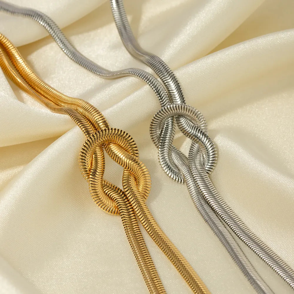 Gold and silver herringbone knot necklaces on satin fabric