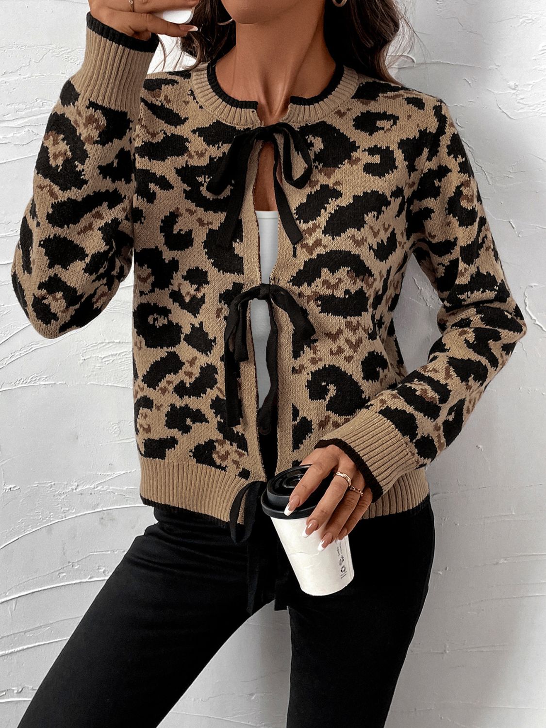 Tan leopard print acrylic knit cardigan with black tie details at the neckline and hem.