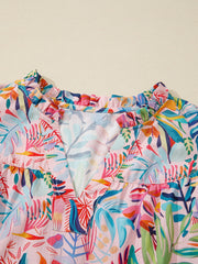 Tropical floral print cotton blouse with ruffled V-neck and short sleeves.