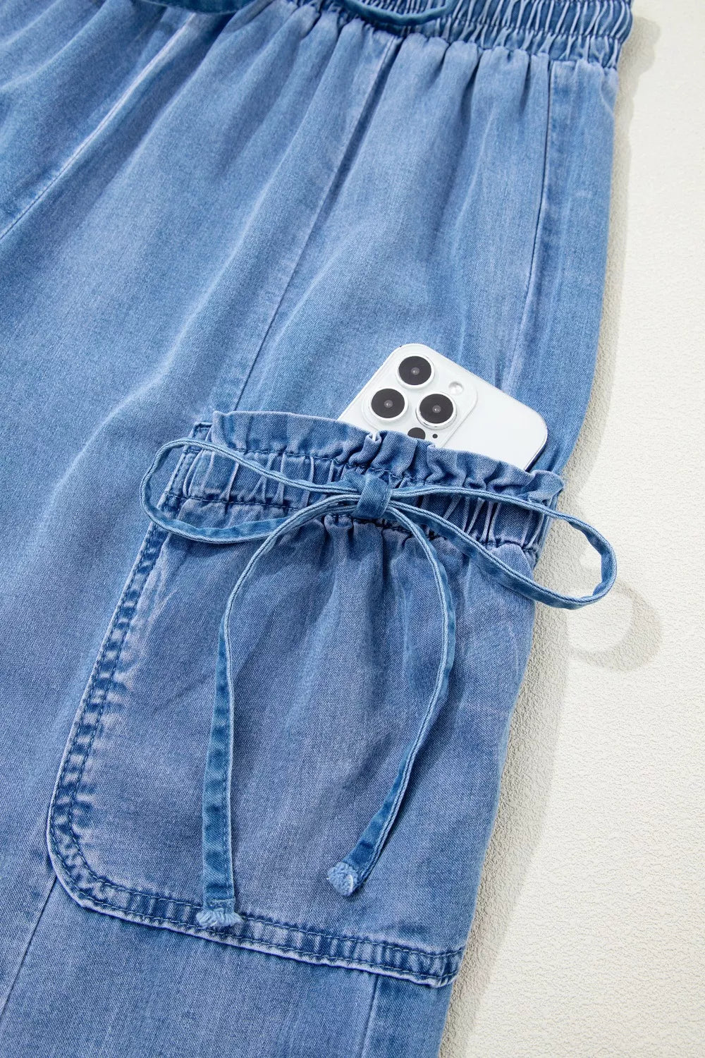 Light wash denim maternity cargo jeans with drawstring waist and cinched cargo pocket.
