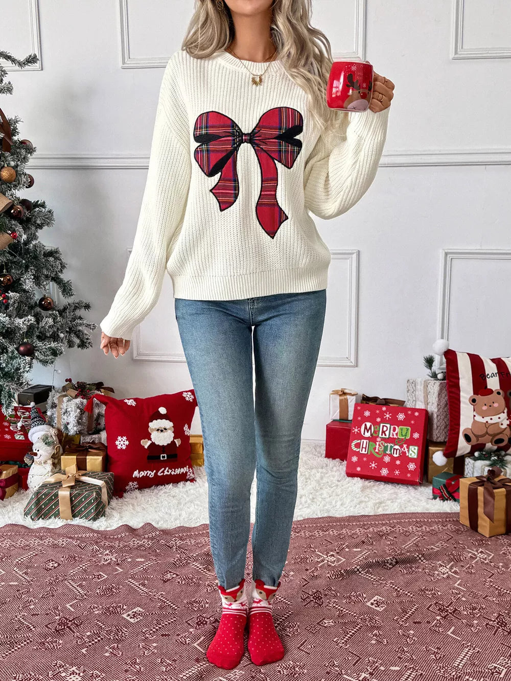 Cream ribbed knit sweater with a large red plaid bow detail, crew neck.