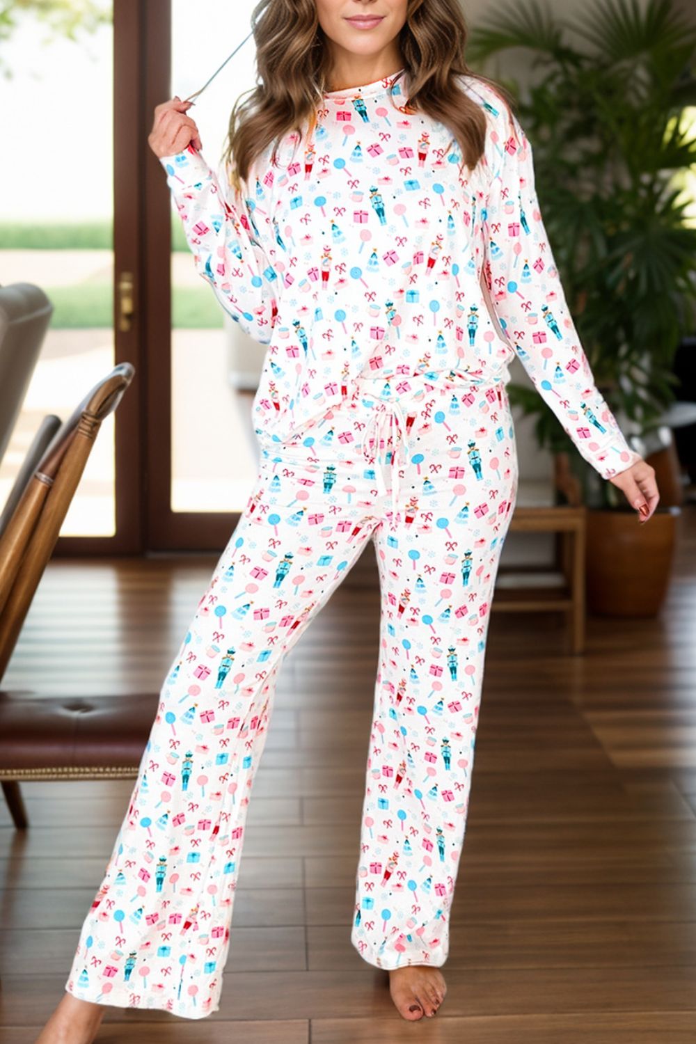 White pajama set with festive nutcracker and candy cane print, long sleeves, drawstring waist, and wide leg pants.