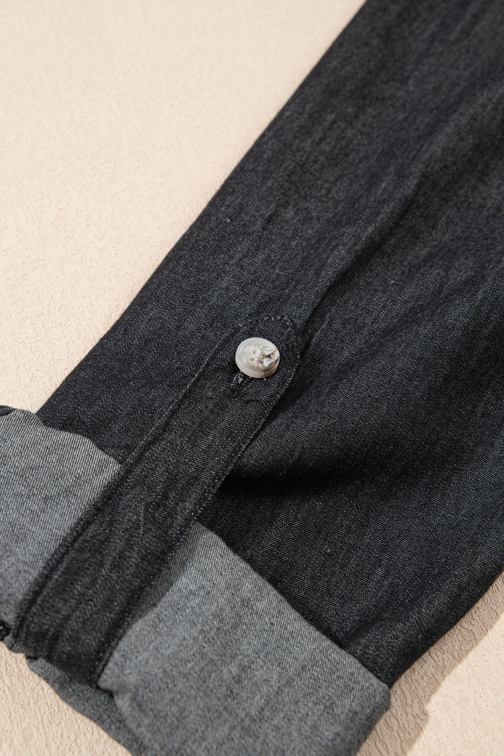 Relaxed black denim shirt with buttoned cuff detail and rolled sleeves.