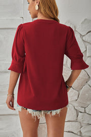 Burgundy puffed sleeve blouse with flared cuffs and a V-neckline.