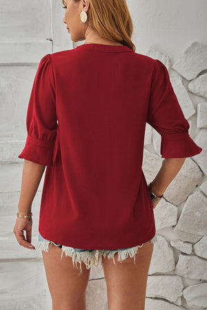 Burgundy puffed sleeve blouse with flared cuffs and a V-neckline.