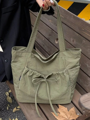 Olive green nylon tote bag with drawstring bow detail and exterior pockets
