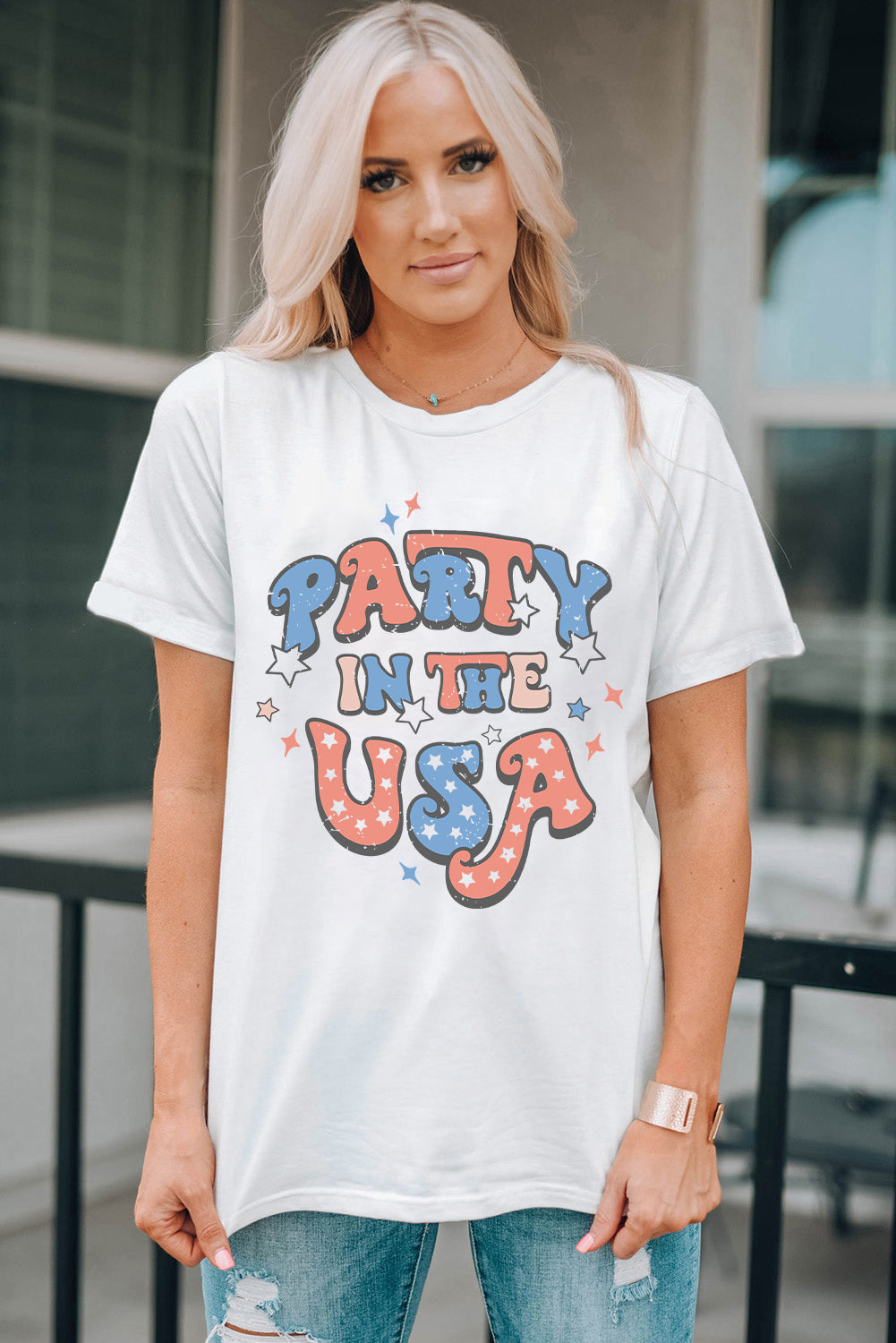 White graphic t-shirt with "Party in the USA" text and stars in red, white, and blue.