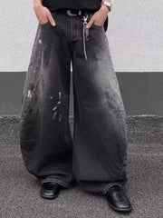 Men's black wide leg distressed jeans with paint splatters and chain detail.