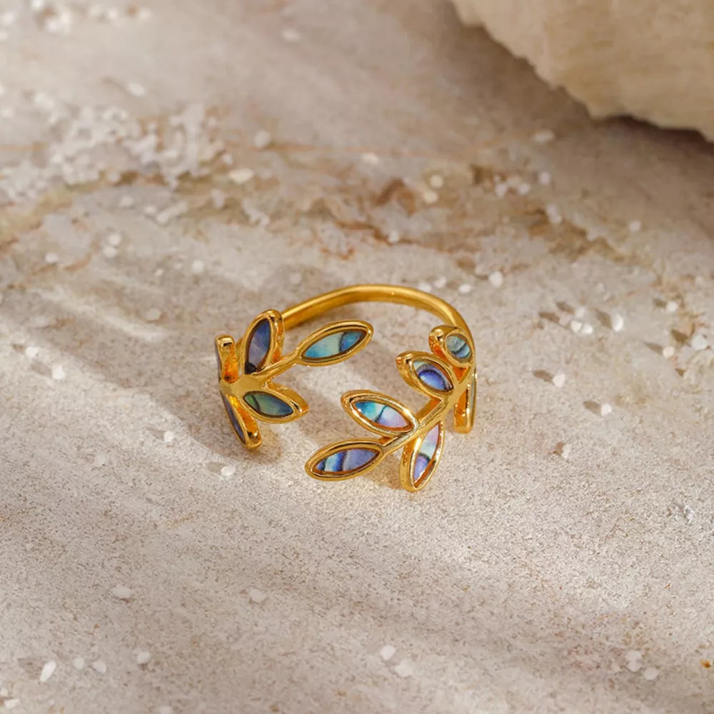 Gold bypass ring with delicate leaf design featuring iridescent blue and purple inlay.