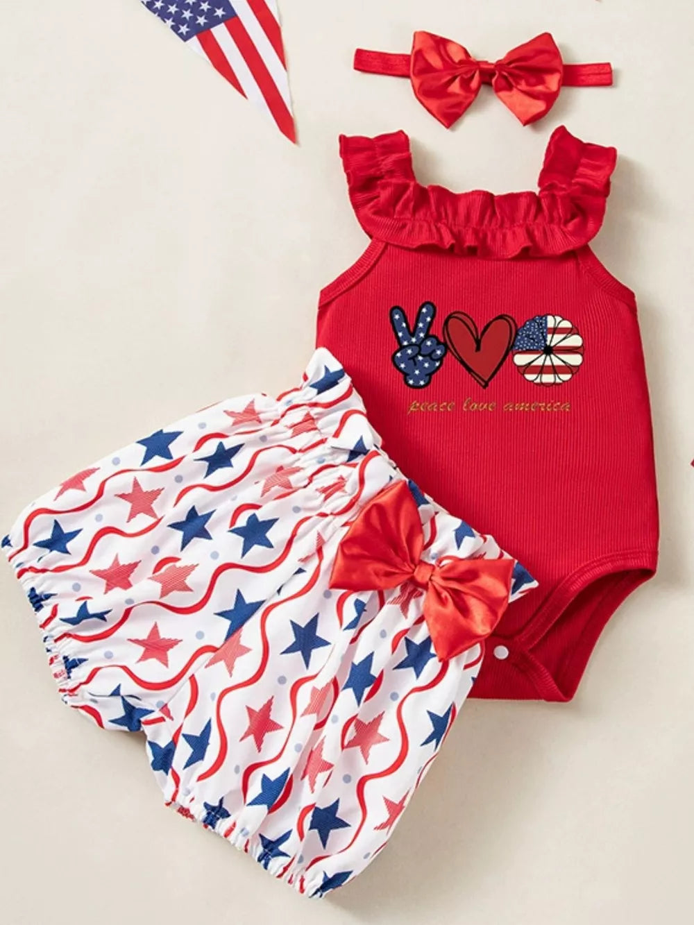 Red patriotic baby set with ruffled neckline, star print bloomer shorts, and bow headband.