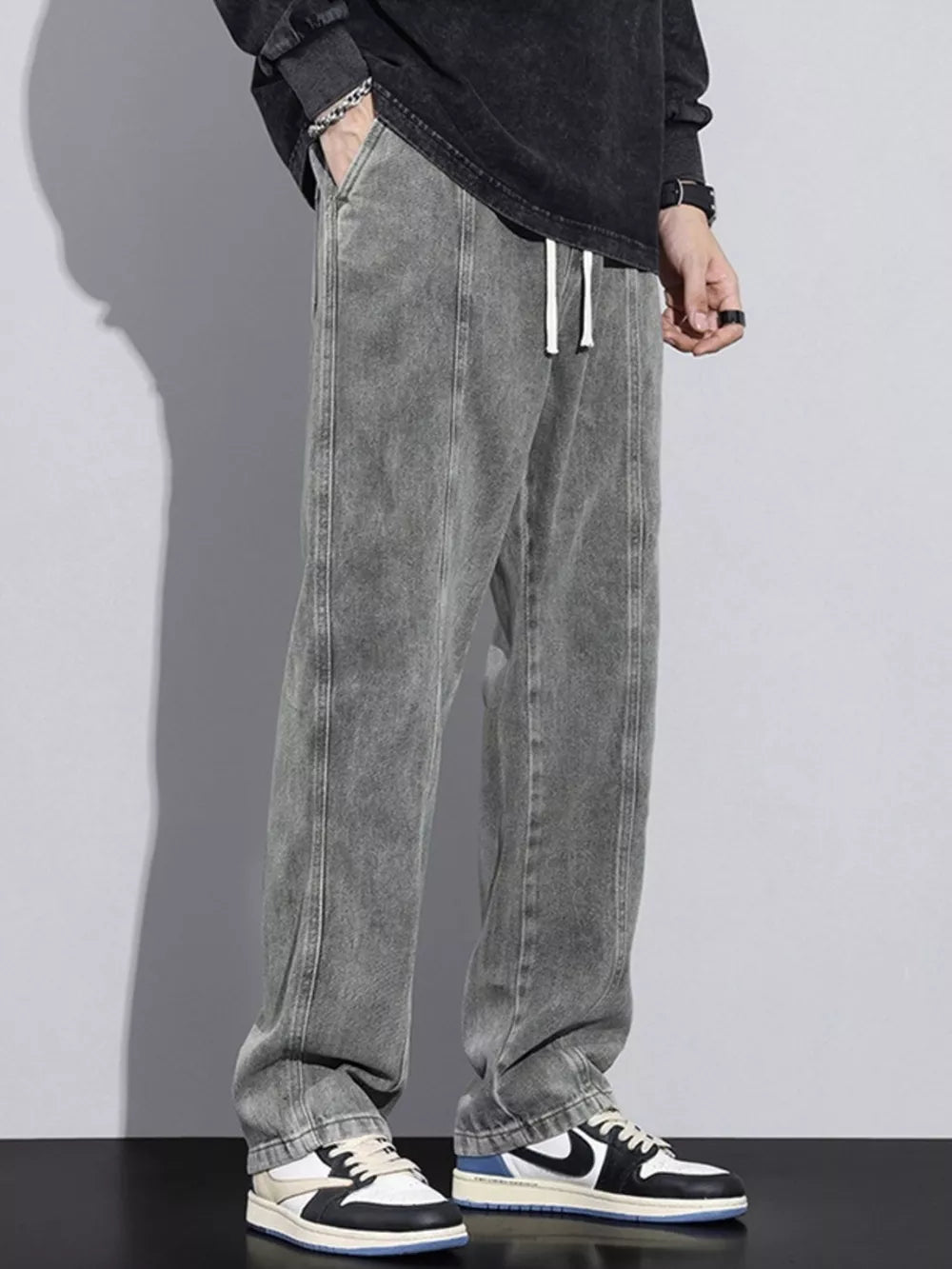 Comfortable relaxed fit jeans in grey denim with white drawstring and vertical seam detail.