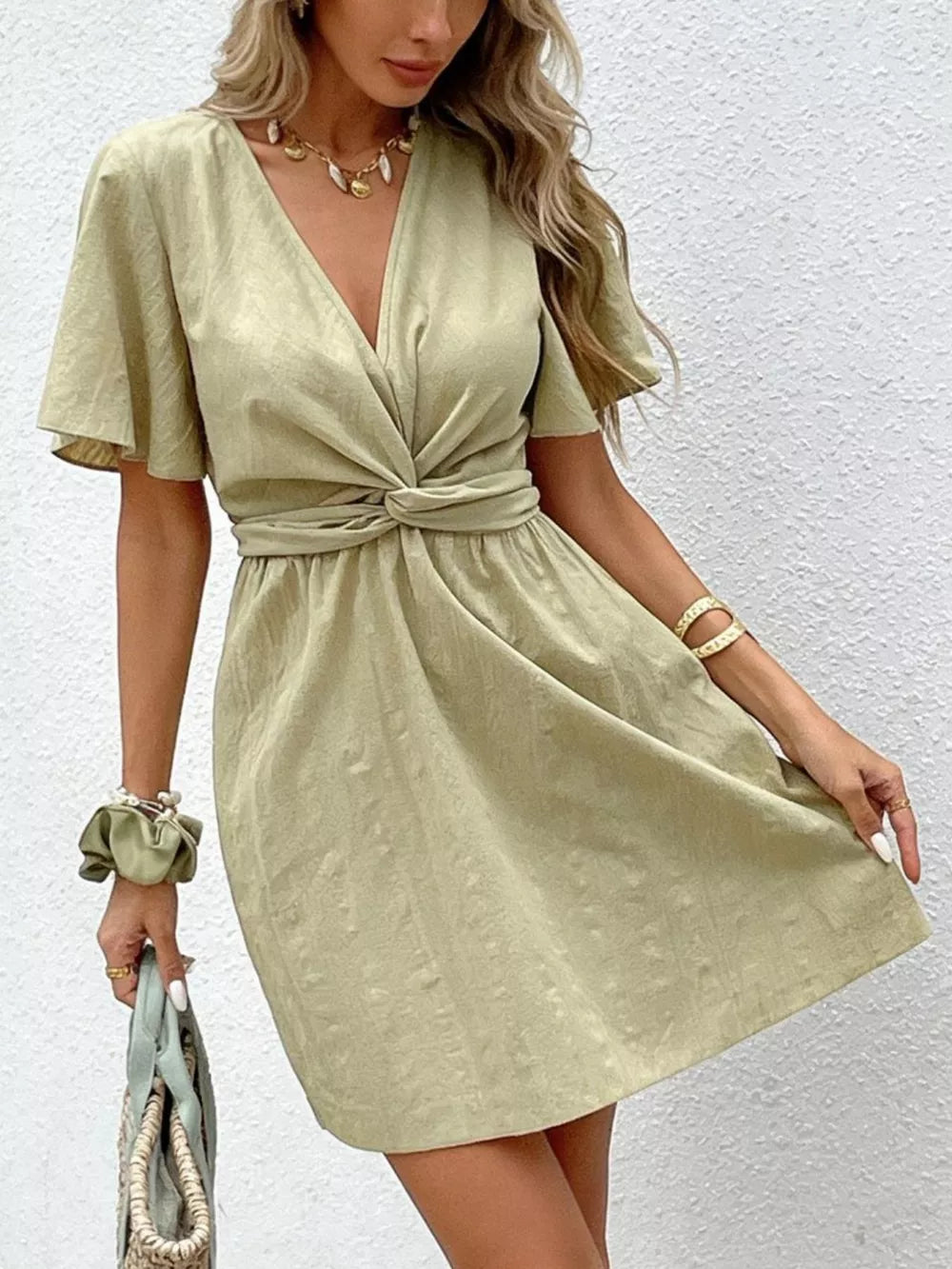 Twist waist mini dress in light green with flutter sleeves and a V-neck.