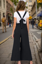 Black wide-leg jumpsuit with tie-back straps and textured fabric