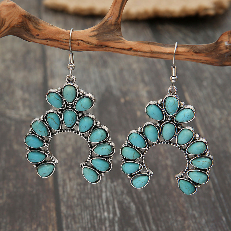 Turquoise crescent dangle earrings with teal stones and silver alloy metal.