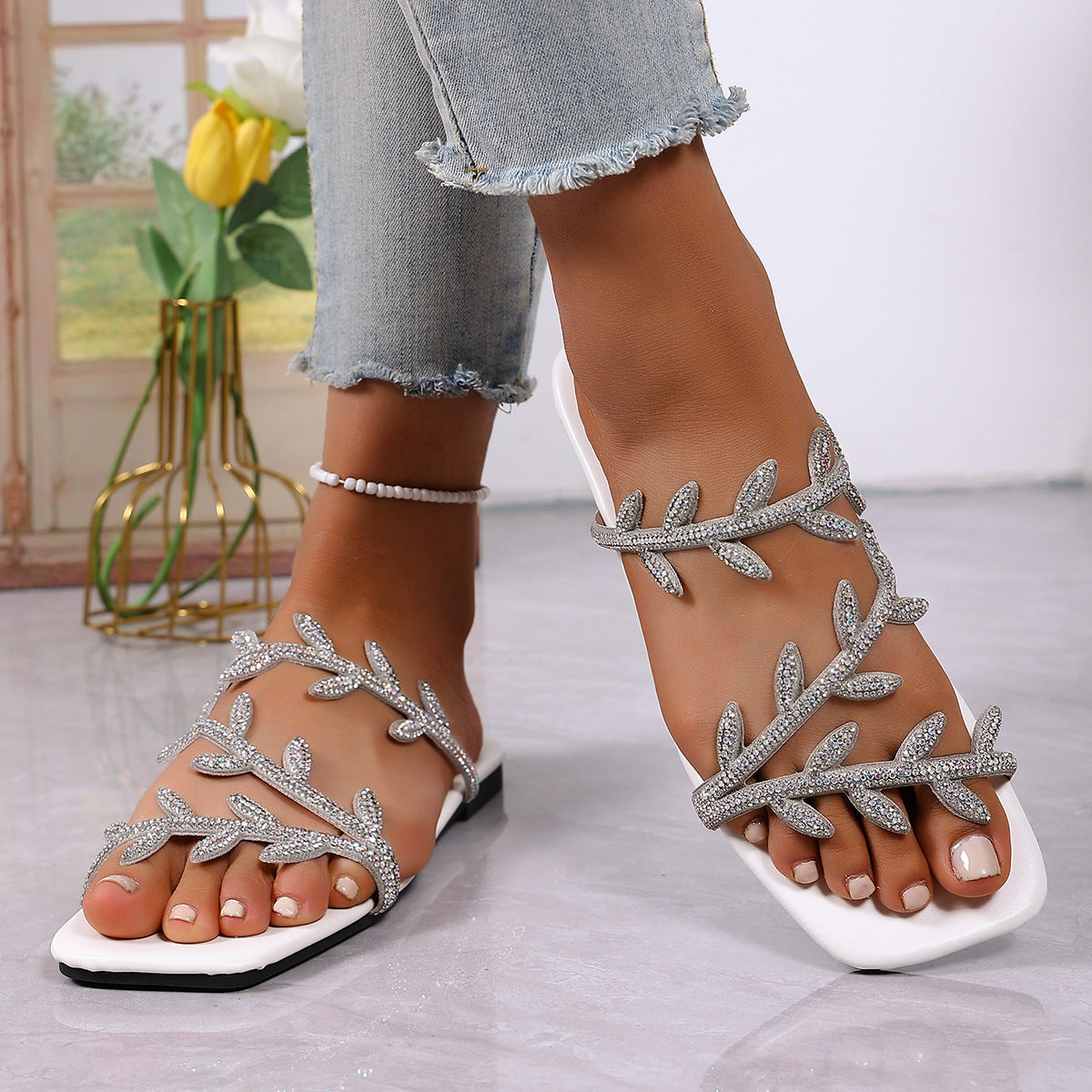 White open toe sandals with rhinestone leaf embellishments and a square toe.