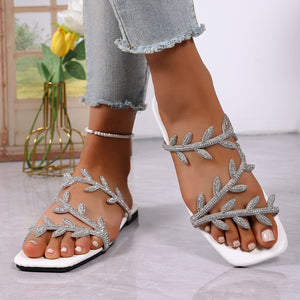 White open toe sandals with rhinestone leaf embellishments and a square toe.