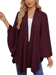 Burgundy knit cape top with draped elegance and wide sleeves, worn over a white tank.