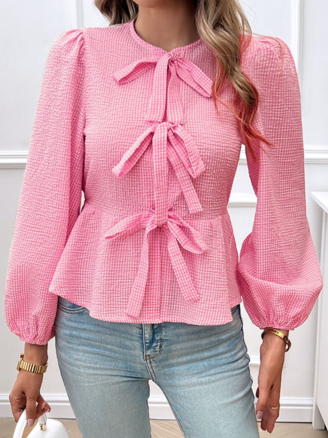 Pink textured peplum blouse with bow details and puff sleeves