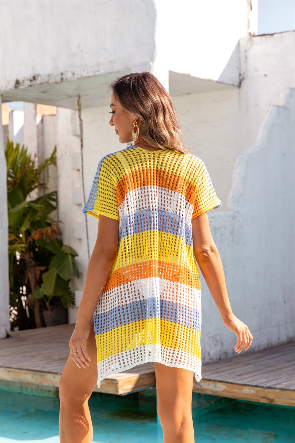 Rainbow crochet beach cover-up with short sleeves and a V-neck in yellow, orange, white, and blue stripes.