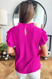 Textured ruffle trim blouse with mock neck and keyhole back.