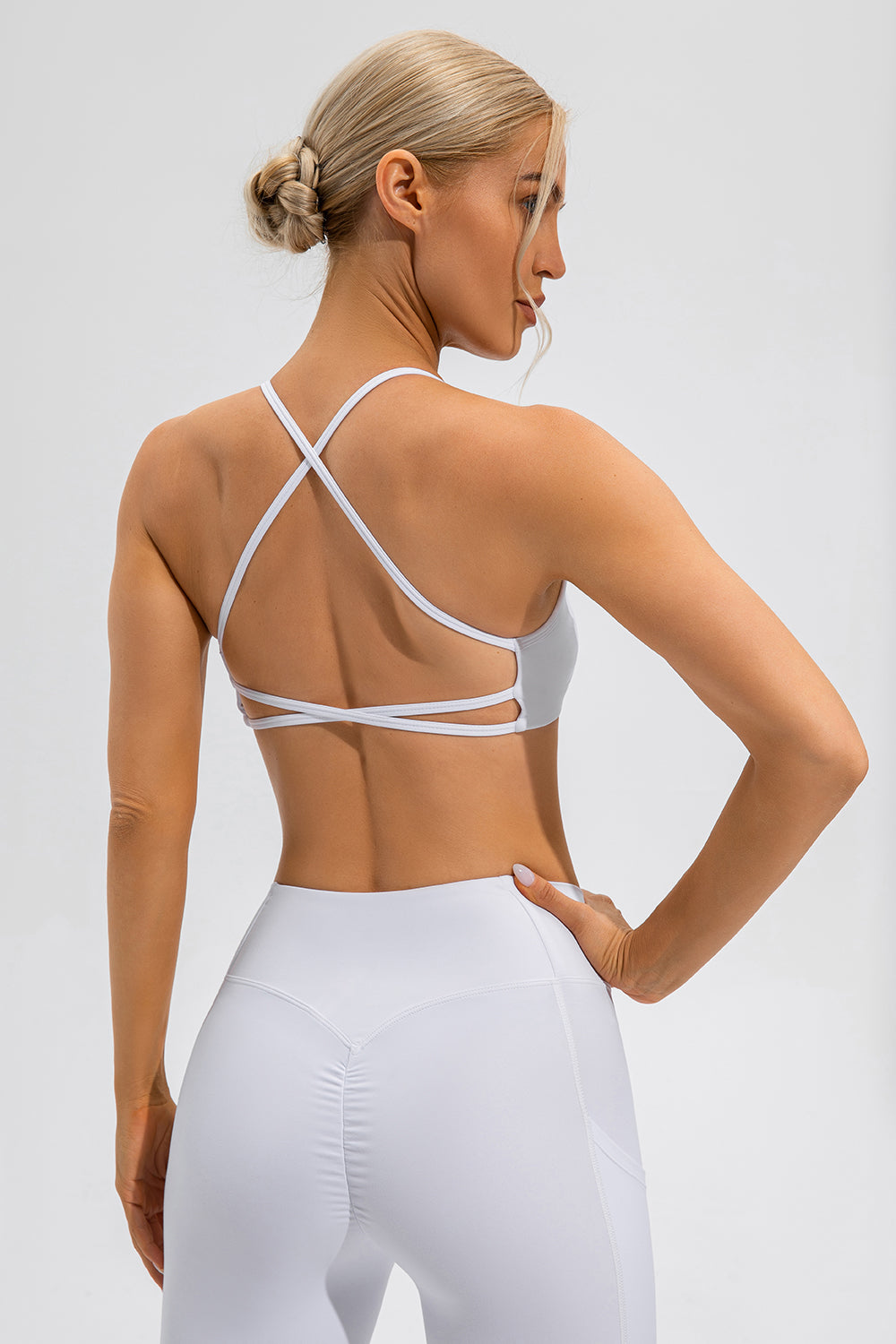 White sports bra with crisscross back straps and a strappy detail.