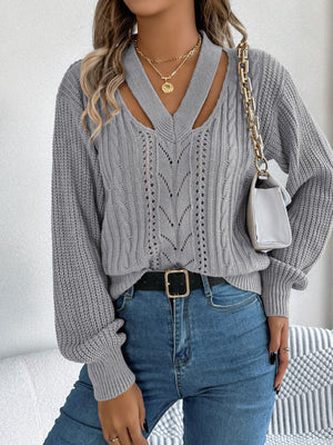 Gray cable knit sweater with cutout neckline and open knit detail.