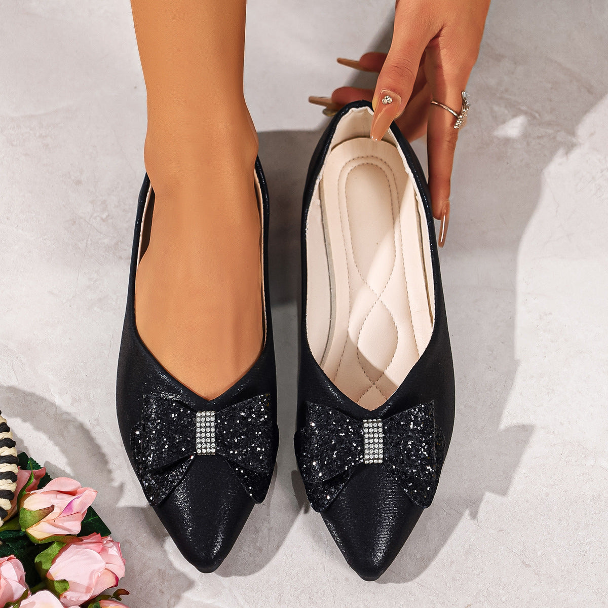 Black pointed toe flats with sparkly bow and rhinestone detail.