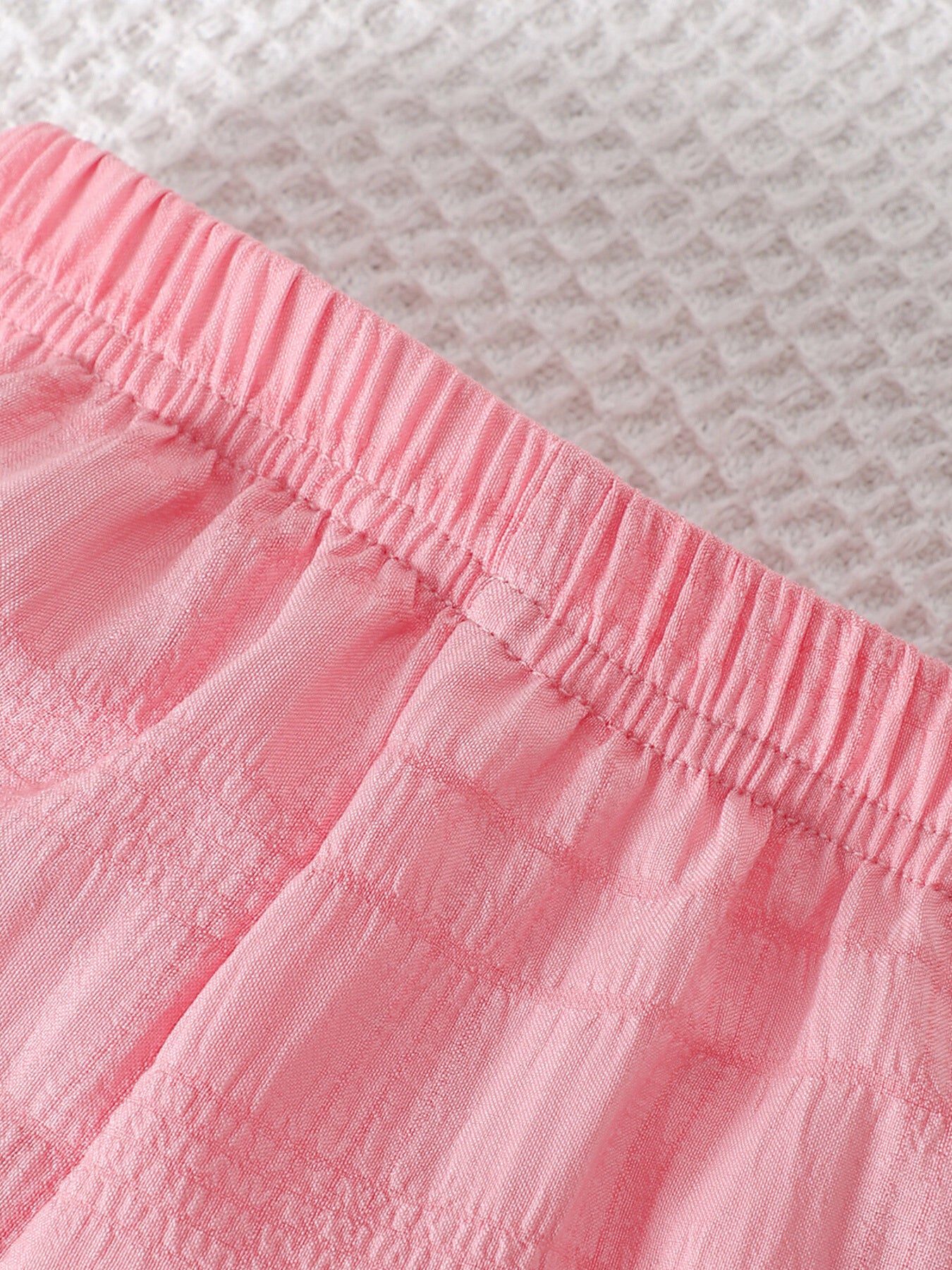 Pink baby pants with elastic waistband and textured fabric detail