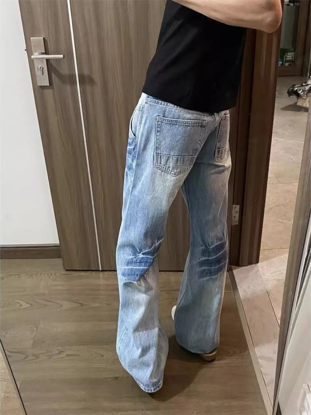 Men's light wash distressed wide leg jeans with patch details.