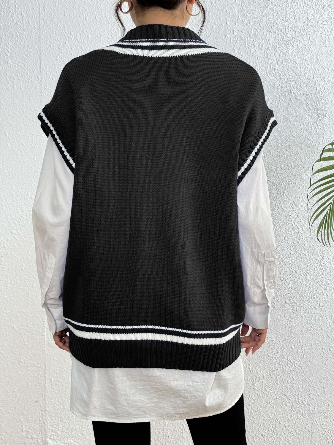 Black acrylic knit vest with varsity stripes and pearl trim, styled over a white shirt.