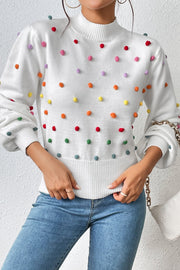 White knit sweater with colorful pom-pom embellishments and mock neck