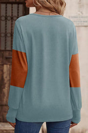 Blue knit sweater with orange colorblock sleeves and button cuffs.