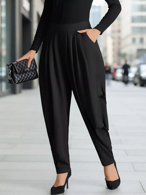 Black ribbed maternity pants with a relaxed fit and pockets, styled with heels and a clutch.