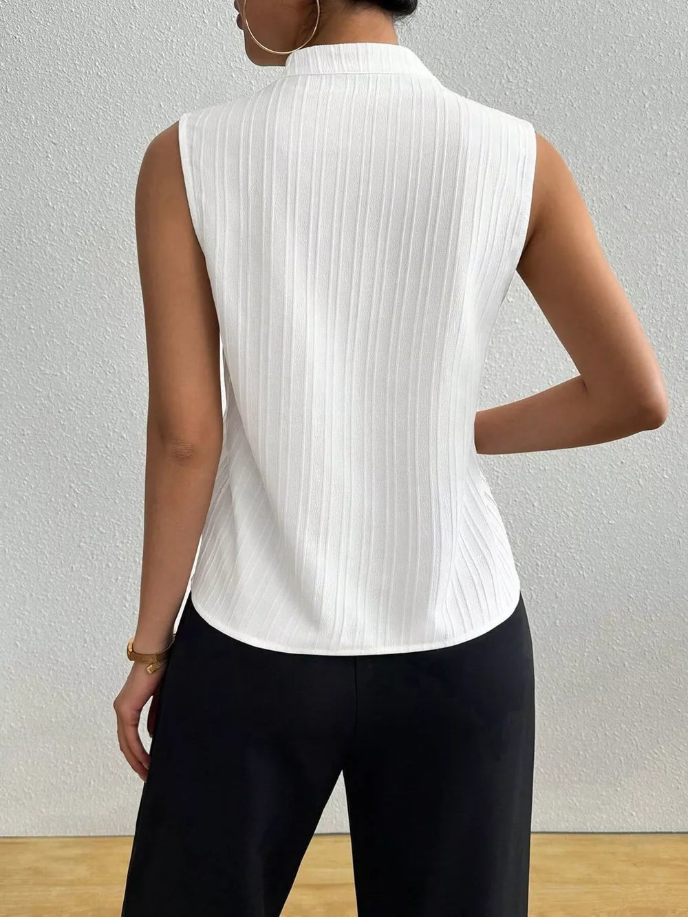 White textured sleeveless blouse with notched V-neck and vertical ribbing detail.