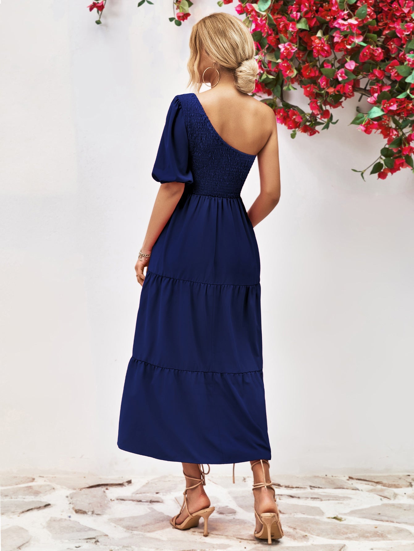 Dark blue smocked bodice tiered one-shoulder dress with puff sleeve and midi length.