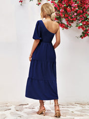Dark blue smocked bodice tiered one-shoulder dress with puff sleeve and midi length.