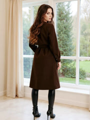 Brown tailored double-breasted trench coat with waist tie and buttoned cuffs.